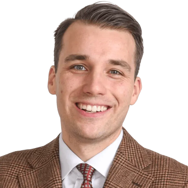 Muotokuva hymyilevästä nuoresta miehestä ruskeassa ruututakissa, valkoisessa paidassa ja punakirjavassa solmiossa mustalla taustalla.